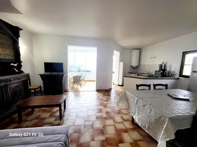 a living room with a table and a kitchen at T2 bord de mer Agosta in Albitreccia
