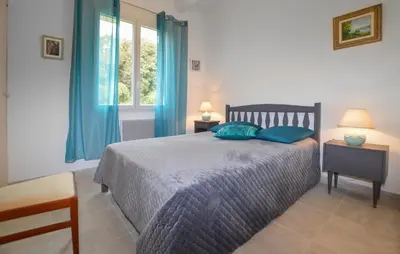 a bedroom with a bed with blue pillows and a window at 2 Bedroom Stunning Home In San-Giuliano in San-Giuliano