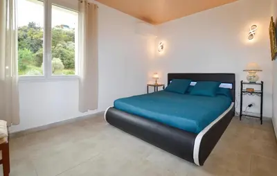 a bedroom with a bed with blue sheets and a window at 2 Bedroom Stunning Home In San-Giuliano in San-Giuliano