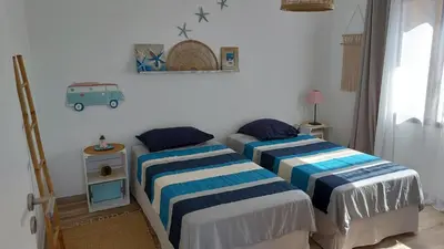 a bedroom with two beds and a table with a lamp at Maison proche de la mer in Pianottoli-Caldarello