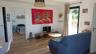 a living room with a blue couch and a tv at Maison proche de la mer in Pianottoli-Caldarello