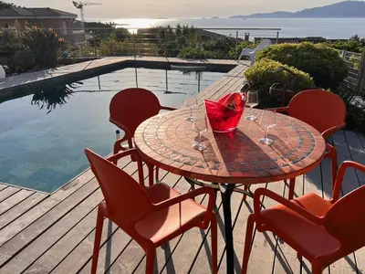 a table with chairs and a glass of wine on a patio at villa 4 etoiles 3 chambres vue mer ajaccio in Pietrosella