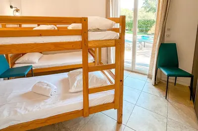 a room with three bunk beds with a chair and a window at Villa Amaredda Di Arasu in Sainte-Lucie de Porto-Vecchio