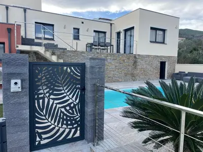 a gate with a design on it in front of a house at Belle Maison avec piscine Furiani in Furiani