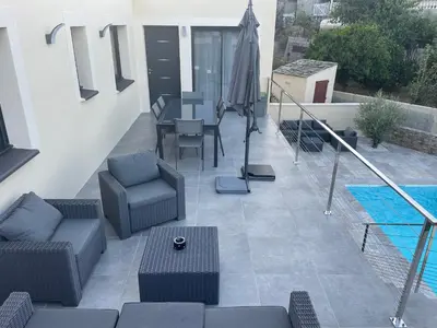 a patio with furniture and a table and a pool at Belle Maison avec piscine Furiani in Furiani