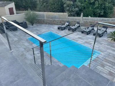 a swimming pool with two chairs and an umbrella at Belle Maison avec piscine Furiani in Furiani
