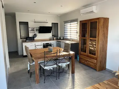 a kitchen and dining room with a wooden table and chairs at Belle Maison avec piscine Furiani in Furiani