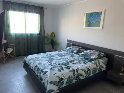 a bedroom with a bed with a blue and white comforter at Belle Maison avec piscine Furiani in Furiani