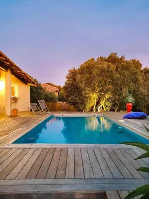 a swimming pool with a wooden deck next to a house at La Casa Soliam in Bonifacio