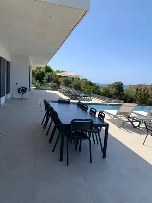 a patio with a table and chairs next to a pool at VILLA IMPERIALE vue mer piscine in Pietrosella