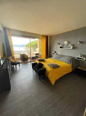 a bedroom with a yellow bed and a large window at Le bord de mer in Propriano