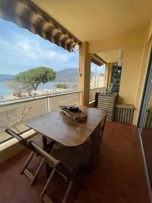 a wooden table on a balcony with a view of the ocean at Le bord de mer in Propriano