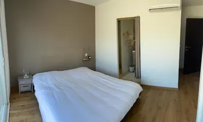 a bedroom with a white bed and a mirror at Maison de Vacances Avec Piscine Privée en Corse, BORGO in Borgo