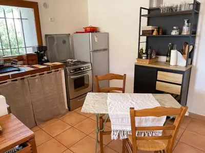 a kitchen with a stove and a table with chairs at Charmante maison de village in Porto-Vecchio