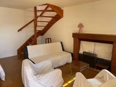 a living room with a bed and a staircase at Charmante maison de village in Porto-Vecchio
