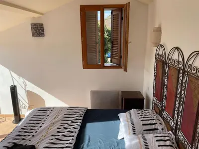a bedroom with a bed and a window at Charmante maison de village in Porto-Vecchio