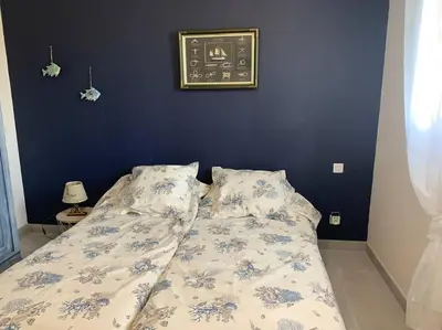a bed in a bedroom with a blue wall at Rez de maison neuve Piscine WiFi Poolhouse en Pierre in Penta-di-Casinca