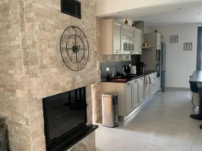 a kitchen with a brick fireplace with a clock on it at Rez de maison neuve Piscine WiFi Poolhouse en Pierre in Penta-di-Casinca
