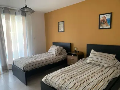 a bedroom with two beds and a window at Rez de maison neuve Piscine WiFi Poolhouse en Pierre in Penta-di-Casinca