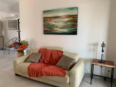 a couch in a living room with a painting on the wall at Rez de maison neuve Piscine WiFi Poolhouse en Pierre in Penta-di-Casinca