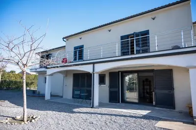 a white house with black doors and a balcony at Rez de maison neuve Piscine WiFi Poolhouse en Pierre in Penta-di-Casinca