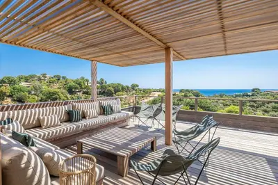 a patio with couches and chairs on a deck at Superbe Villa Porto Vecchio vue mer plage à pied in Porto-Vecchio