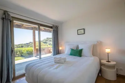 a bedroom with a large bed with a large window at Superbe Villa Porto Vecchio vue mer plage à pied in Porto-Vecchio