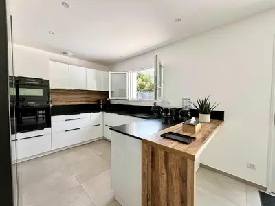 a kitchen with white cabinets and a wooden counter top at Casamea - Villa Familiale, Piscine, 15 min Ajaccio in Alata