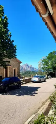 two cars parked on a street with mountains in the background at U pozzu hôtel in Evisa