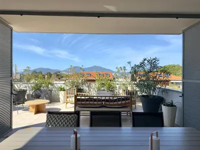a patio with a table and chairs on a balcony at Rare grand appartement standing terrasse et jardin - Porticcio proche mer in Porticcio