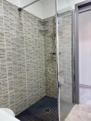 a shower in a bathroom with tiled walls at Rare grand appartement standing terrasse et jardin - Porticcio proche mer in Porticcio