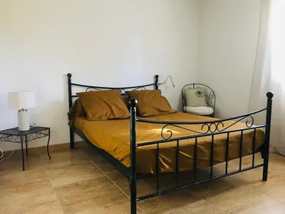 a black bed with a yellow blanket and a side table at Rez de chaussez de villa 4 personnes mer in Sorbo-Ocagnano
