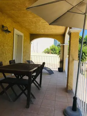 a patio with a table and chairs and an umbrella at Rez de chaussez de villa 4 personnes mer in Sorbo-Ocagnano