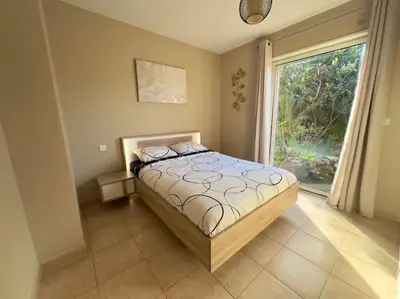 a bedroom with a bed and a large window at 72 m2 Centre-ville avec jardin in Porto-Vecchio