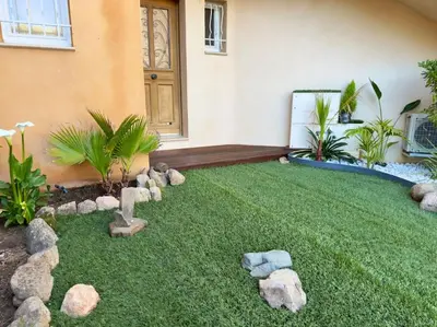 a yard with rocks on the grass in front of a house at 72 m2 Centre-ville avec jardin in Porto-Vecchio