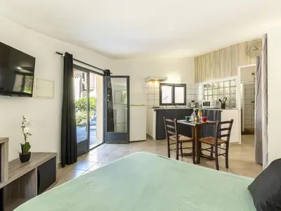 a bedroom with a bed and a kitchen with a table at Studio Germaine by Interhome in Porto-Vecchio