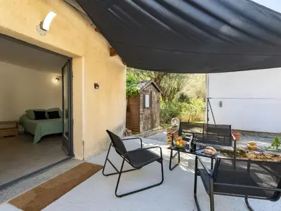 a patio with a table and chairs under a large umbrella at Studio Germaine by Interhome in Porto-Vecchio