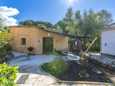 a patio with a house with a black canopy at Studio Germaine by Interhome in Porto-Vecchio