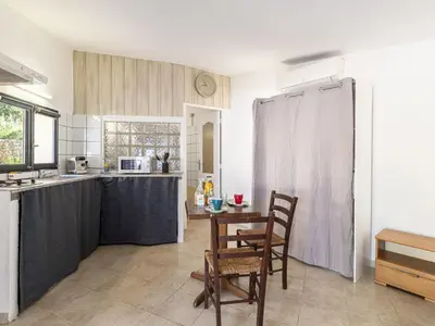 a kitchen with a table and chairs and a kitchen with a counter at Studio Germaine by Interhome in Porto-Vecchio