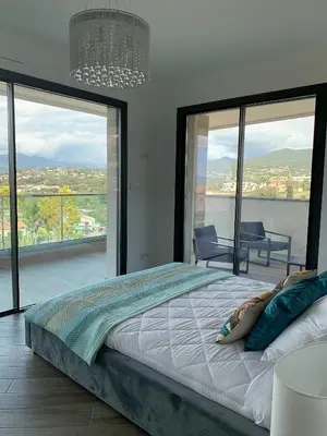 a bedroom with a large bed and large windows at PORTICCIO Maison vue mer in Porticcio