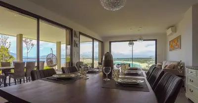 a dining room with a table and chairs and windows at PORTICCIO Maison vue mer in Porticcio