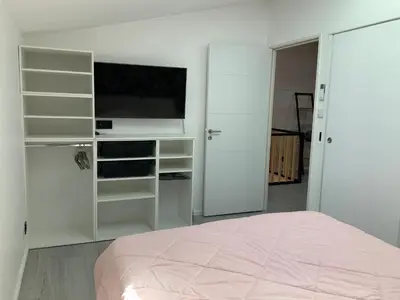 a white bedroom with a flat screen tv and a bed at Villa STEVAN in Bonifacio