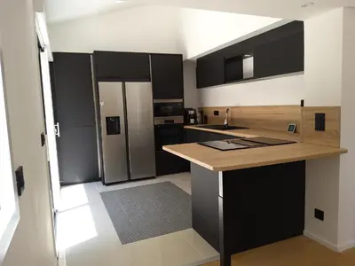 a kitchen with black and white cabinets and a refrigerator at Villa STEVAN in Bonifacio
