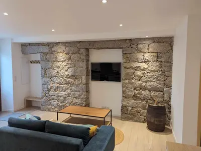 a living room with a couch and a stone wall at Appartement proche de Porto-Vecchio in Porto-Vecchio