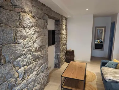 a living room with a stone wall and a table at Appartement proche de Porto-Vecchio in Porto-Vecchio