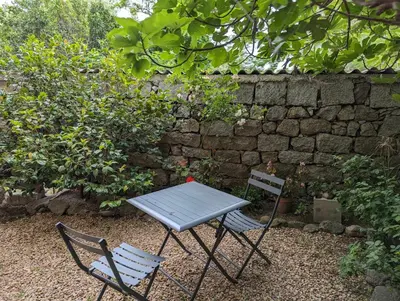 a table and two chairs in front of a stone wall at Appartement proche de Porto-Vecchio in Porto-Vecchio