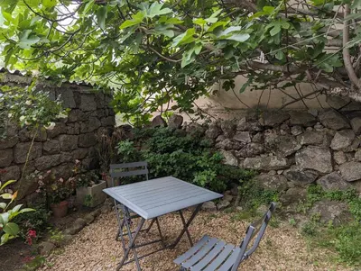 a table and two chairs next to a stone wall at Appartement proche de Porto-Vecchio in Porto-Vecchio