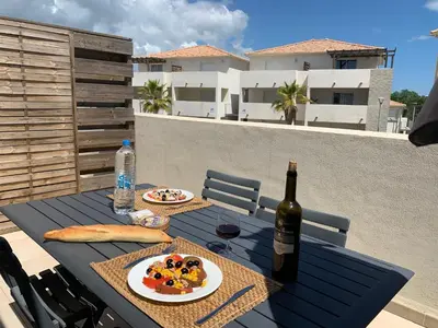 a table with a bottle of wine and a plate of food at Appartement T3 en Corse, Marina di Bravone N131 in Linguizzetta