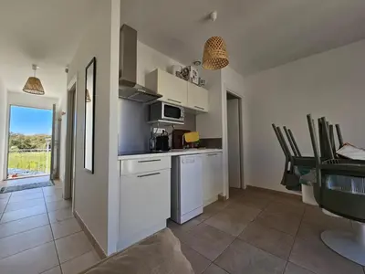 a kitchen with white cabinets and a table with chairs at Appartement T3 en Corse, Marina di Bravone N131 in Linguizzetta
