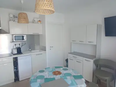 a kitchen with white cabinets and a table in it at Appartement T3 en Corse, Marina di Bravone N131 in Linguizzetta
